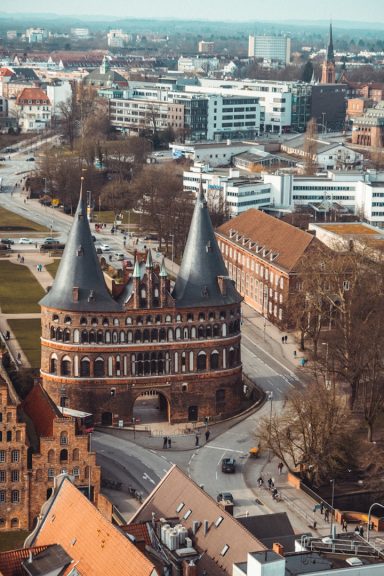 Lübeck Historisches Gebäude mit zwei Türmen, umgeben von modernen Stadtstrukturen und Grünflächen.