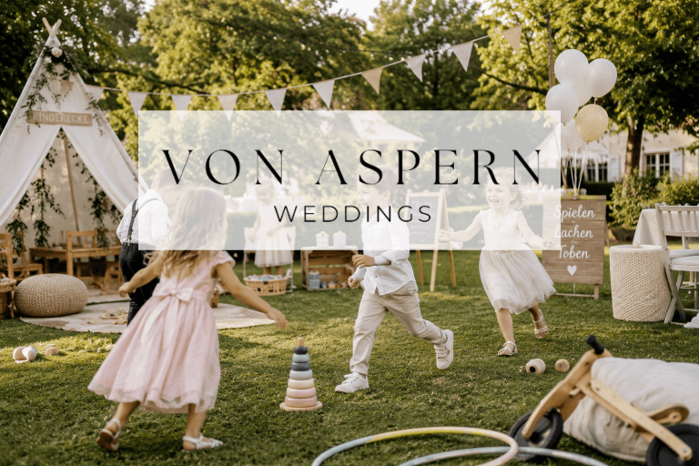 Blog von Aspern Weddings Kinder spielen auf einer Wiese, umgeben von Hochzeitsdekorationen und Zelt.
