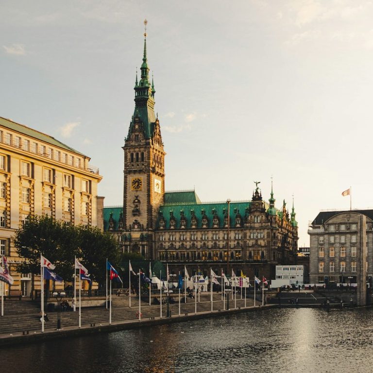 Rathaus Hamburg Historisches Gebäude mit Uhrturm und Flaggen am Wasser in Hamburg.