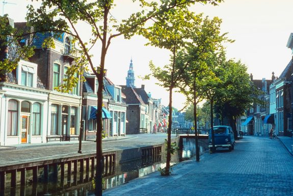 Buxtehude Straße entlang eines Kanals mit Bäumen, historische Gebäude und ein Auto.