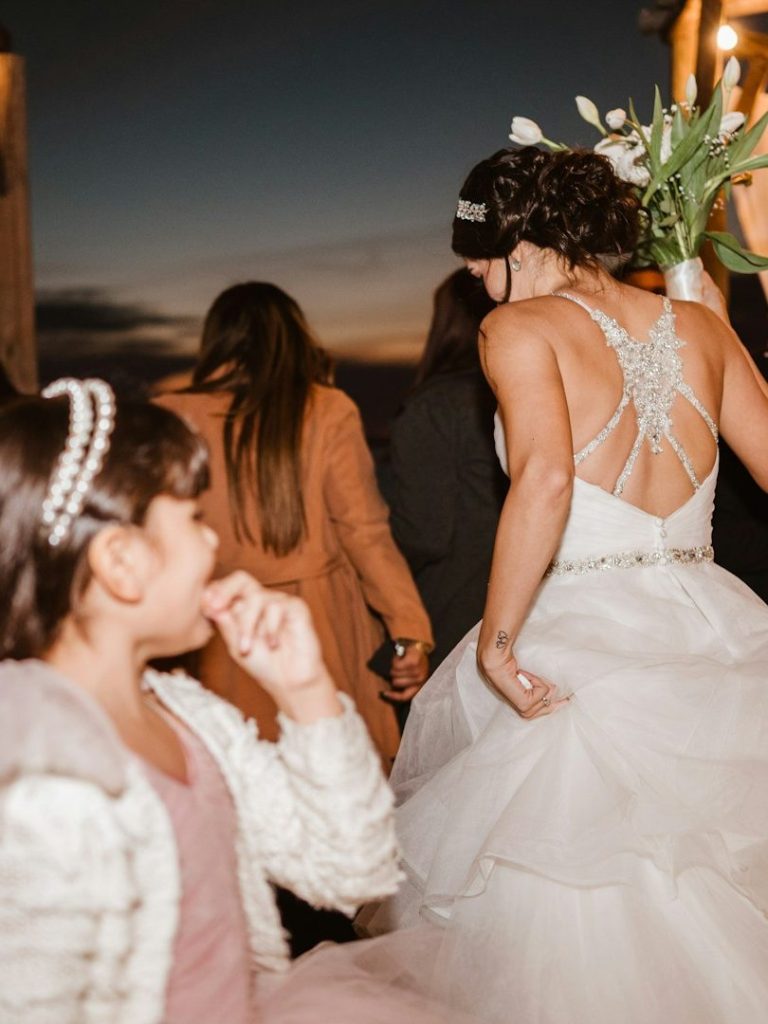 Kinder auf Hochzeiten - eine Bereicherung Eine Braut in einem eleganten Kleid, während ein Mädchen sie neugierig beobachtet.