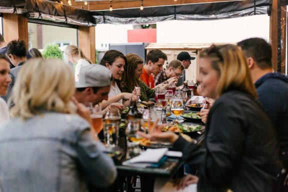 Firmenfeiern Vielbelebte Restaurantterrasse mit Gästen, die Speisen und Getränke genießen.